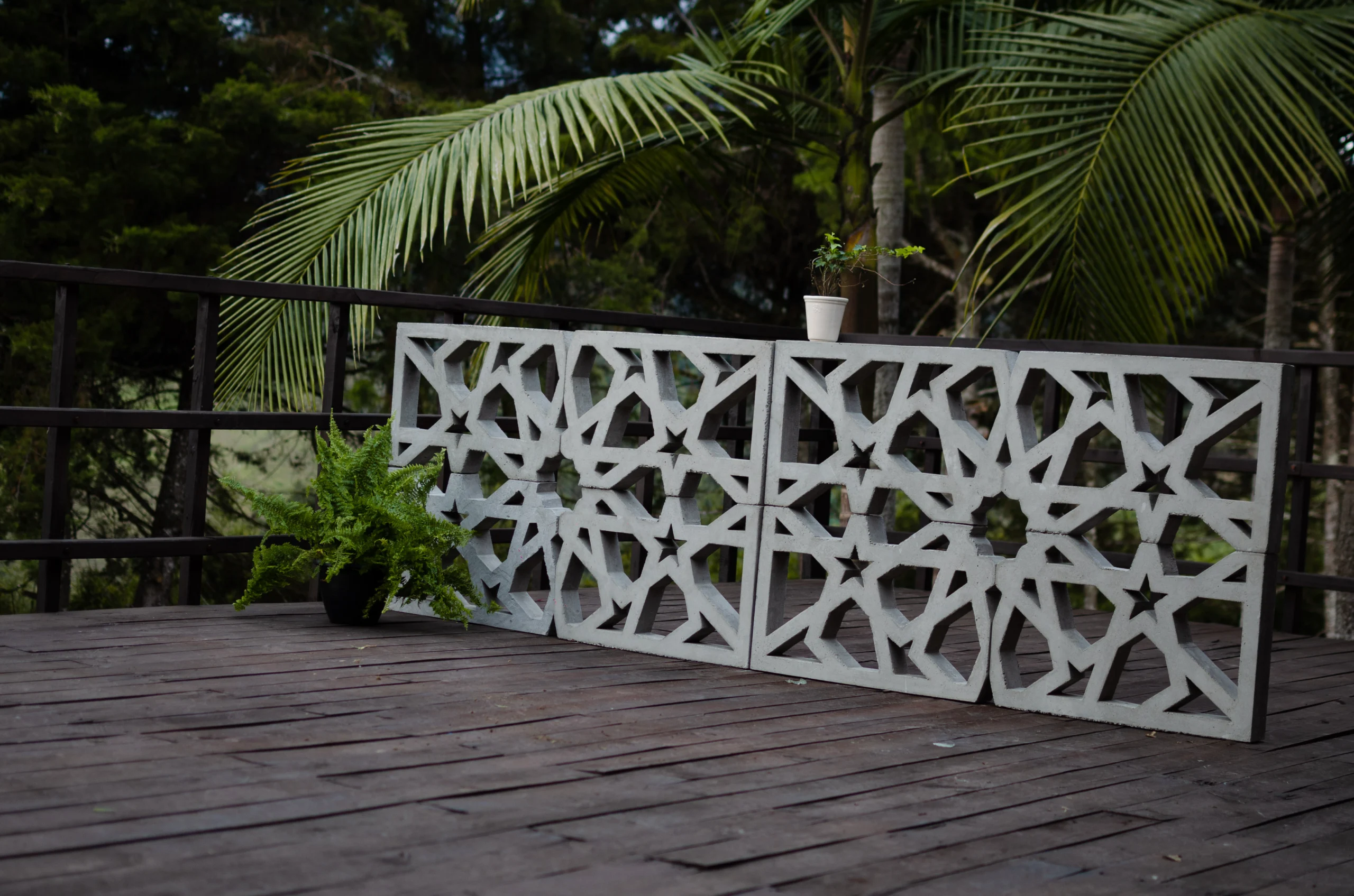 cerramientos-terrazas-celosias-concreto Muro bajo construido con celosías de concreto en una terraza de madera rodeada de palmeras