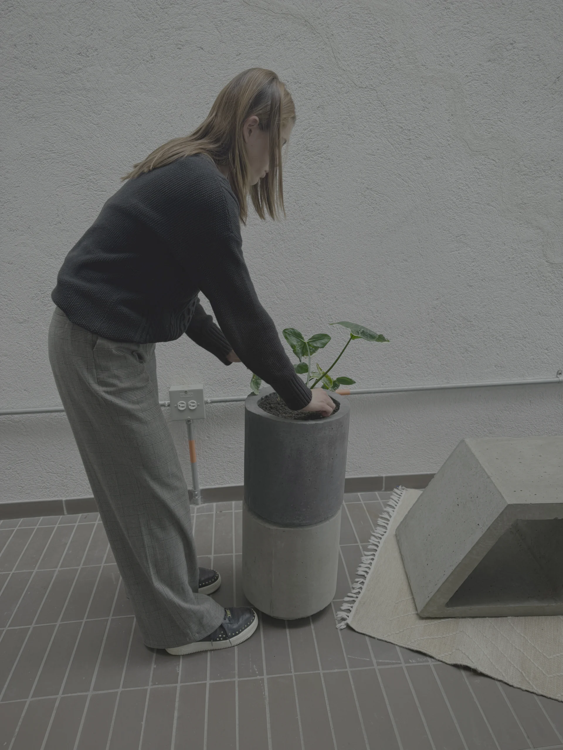 materas-exteriores-concreto-patios Mujer acomodando una planta en la matera cilíndrica de concreto en un patio exterior