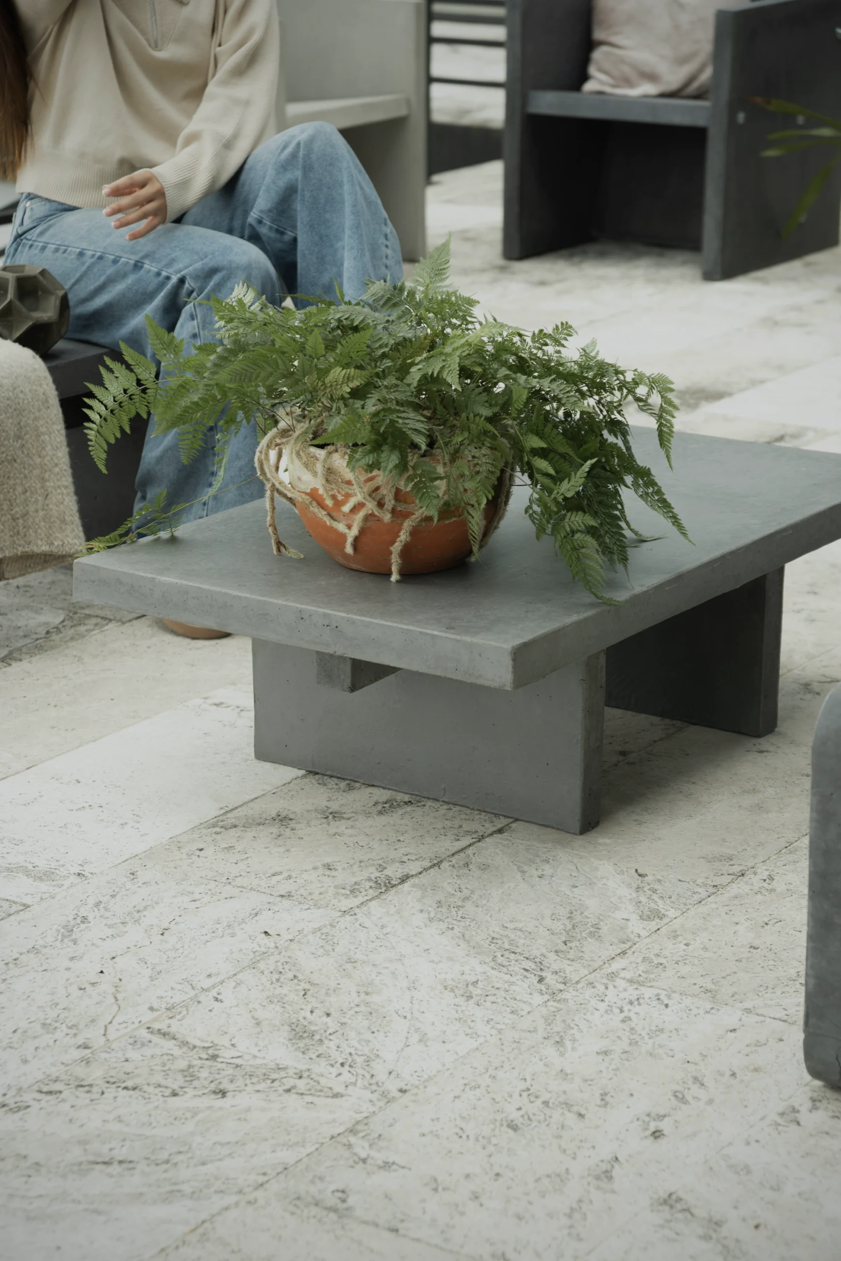 mesa-centro-concreto-rustico-jardines Persona sentada junto a una mesa de centro en concreto con una planta de exterior