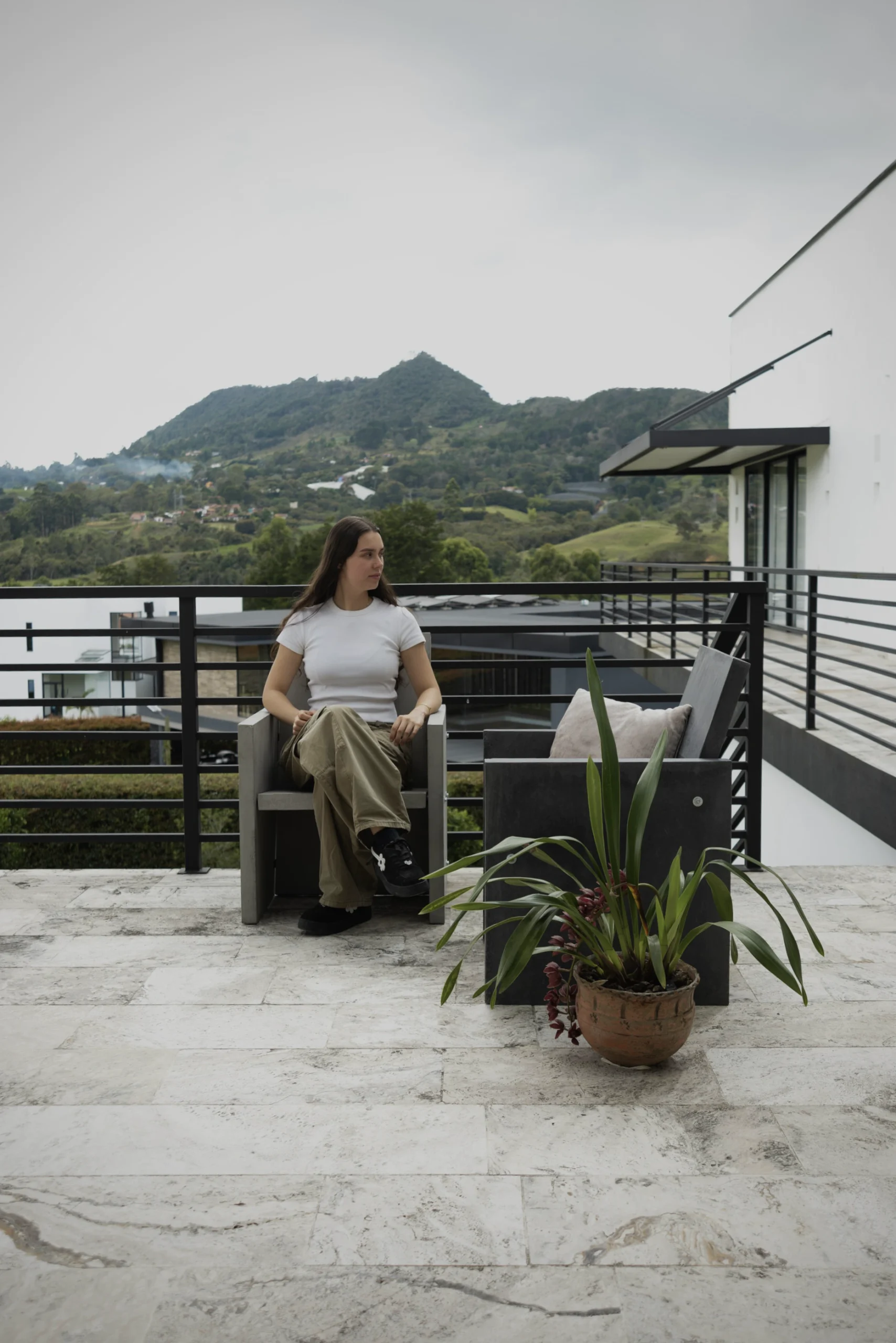 mobiliario-concreto-miradores-balcones Persona relajándose en un balcón con vista a las montañas, sentada en un sillón Imperfecto